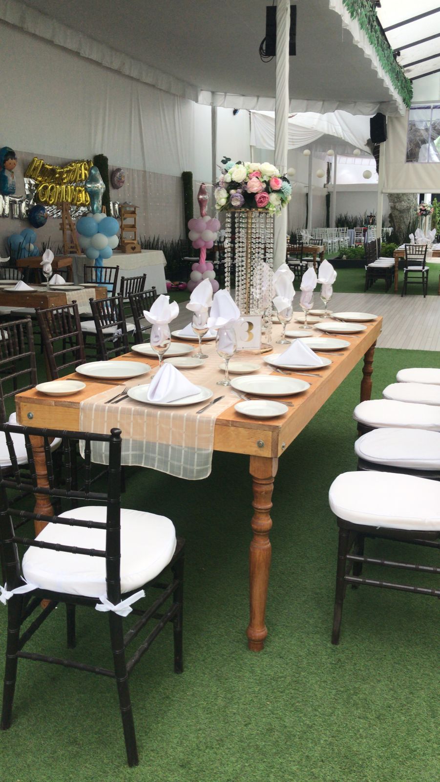Mesa de madera con servilletas blancas, centro de cristal y decoración azul para XV años