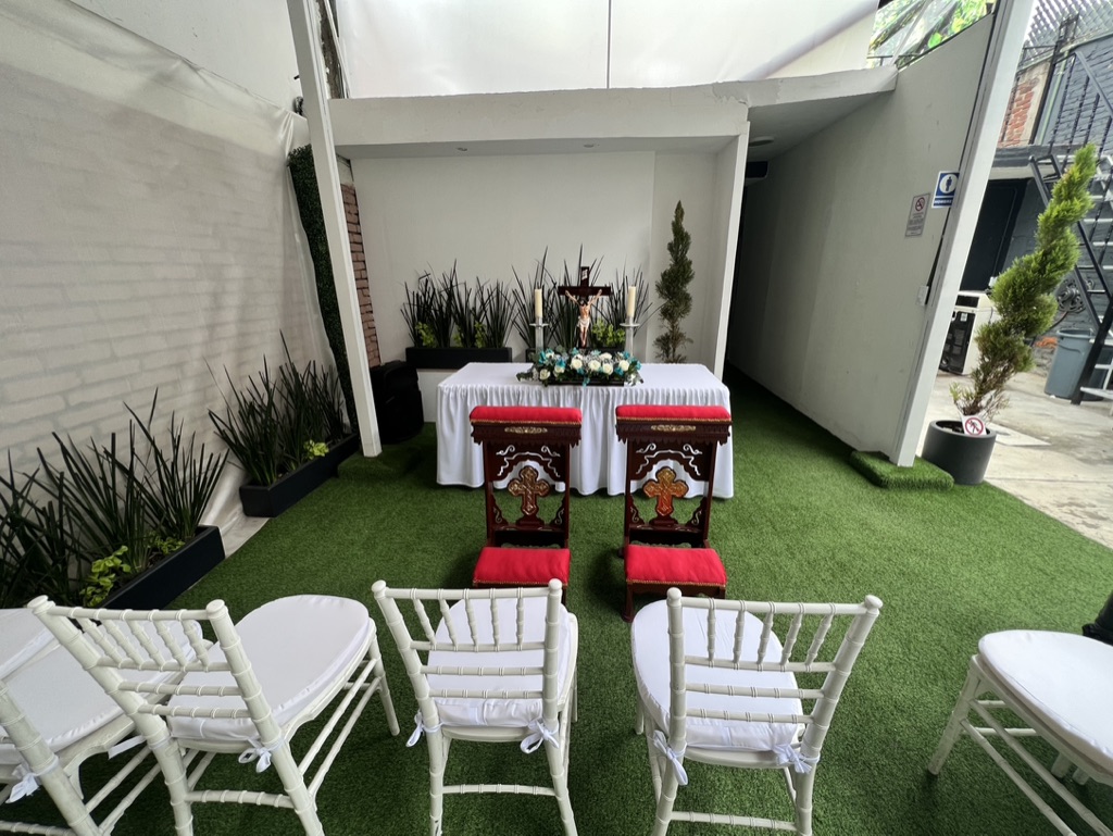 Altar de ceremonia con crucifijo, reclinatorios y sillas bambú blancas en el jardín