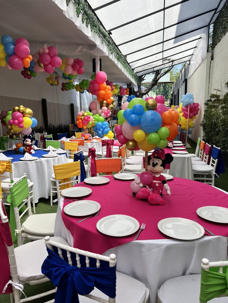 Carpa techada con mesas infantiles, arcos de globos de colores y personajes para fiestas