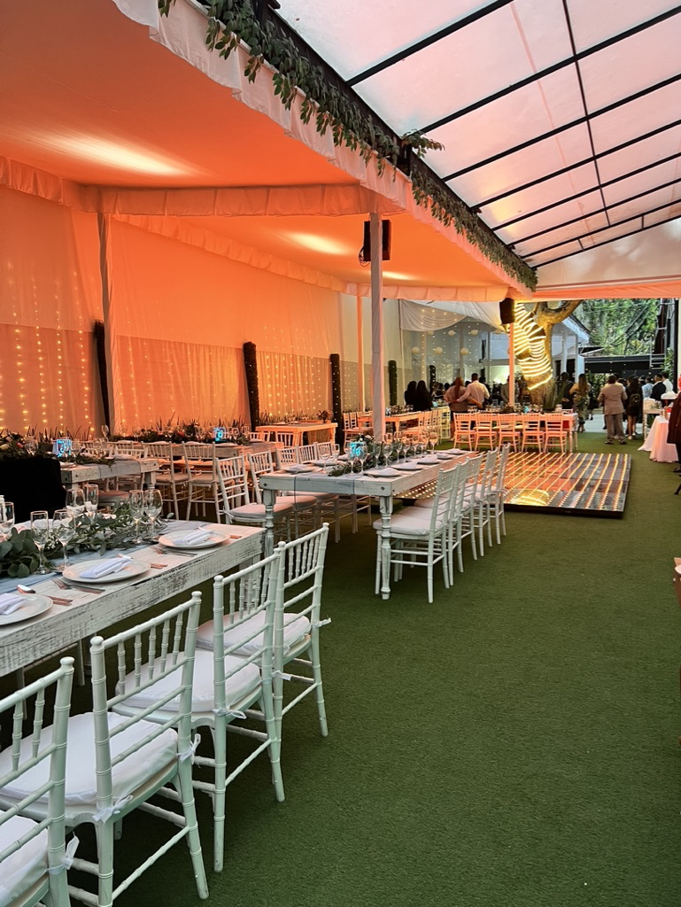 Carpa del jardín con mesas largas vestidas y pista de baile iluminada