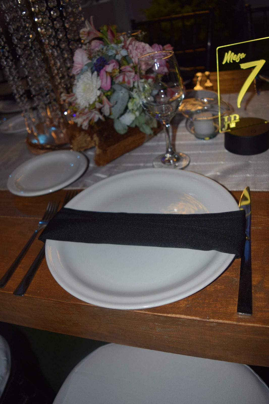 Detalle de plato con servilleta negra y número de mesa luminoso con monograma JP