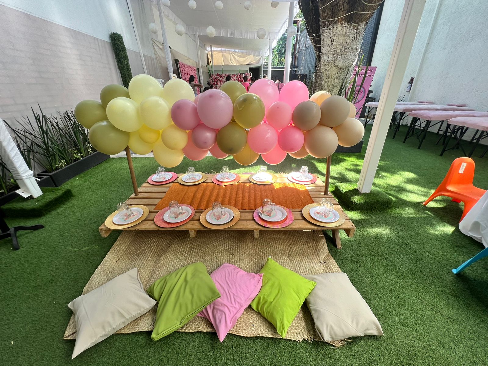 Mesa de dulces baja de madera con globos pasteles y cojines para niños