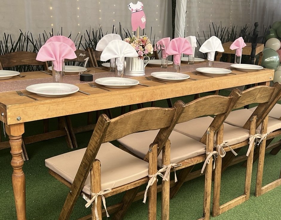 Mesa de madera vintage con sillas plegables y servilletas rosa y blancas