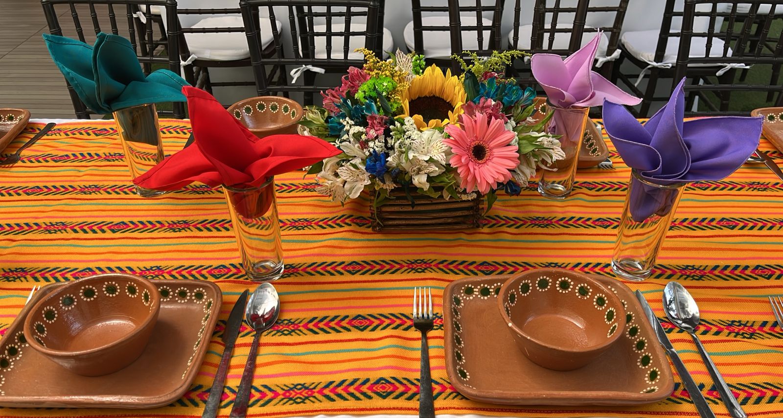 Detalle de mesa con camino amarillo mexicano, vajilla de barro y centro de girasoles