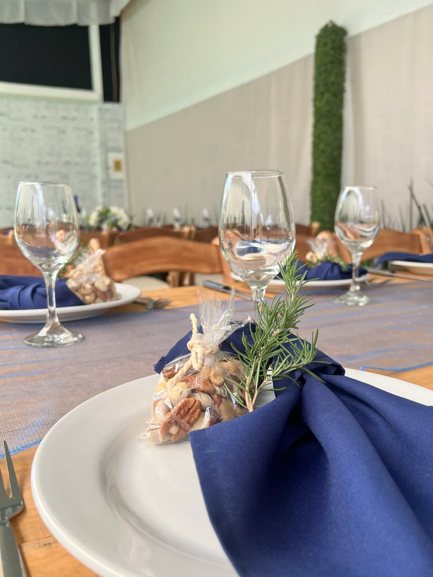 Detalle de plato con servilleta azul marino, romero y copas de vino