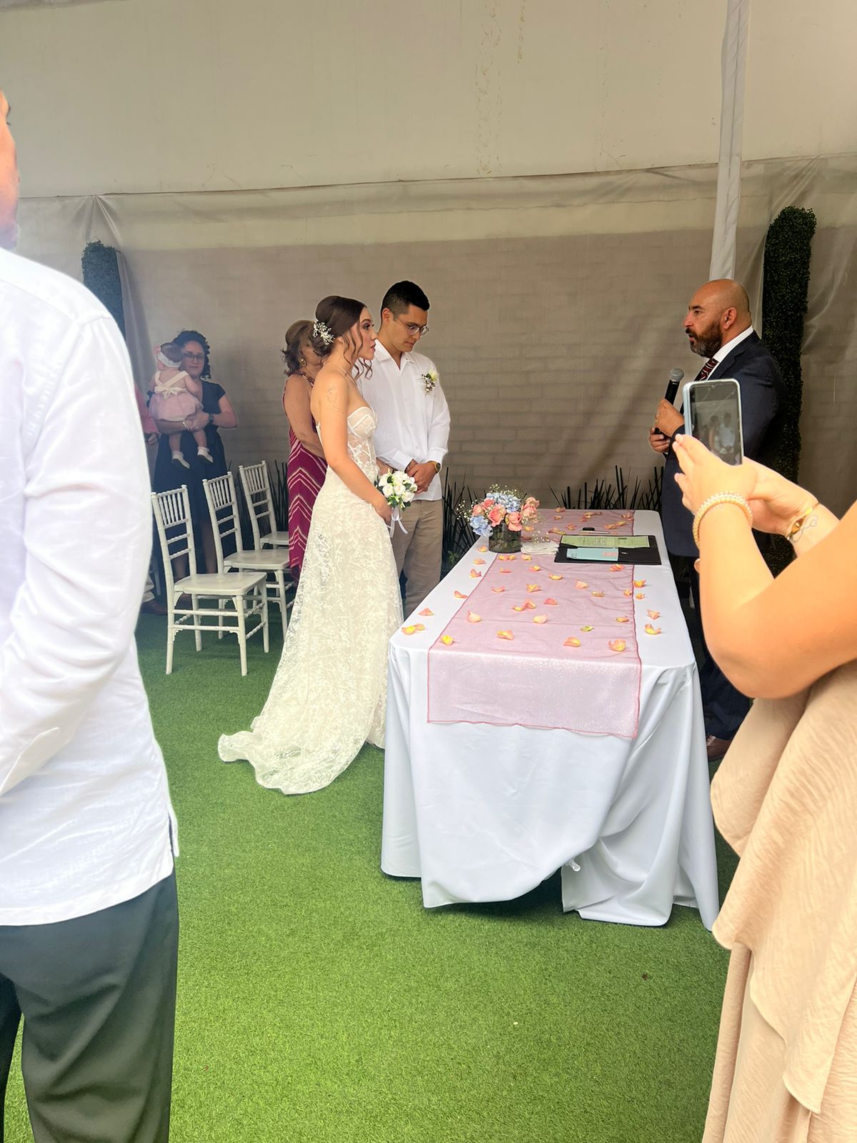 Matrimonio civil con los novios frente a la mesa de firmas con pétalos rosas