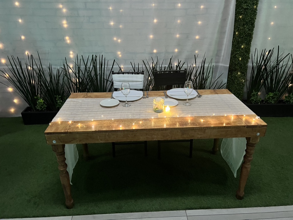 Mesa rústica de madera con camino de luces cálidas y velas en el jardín