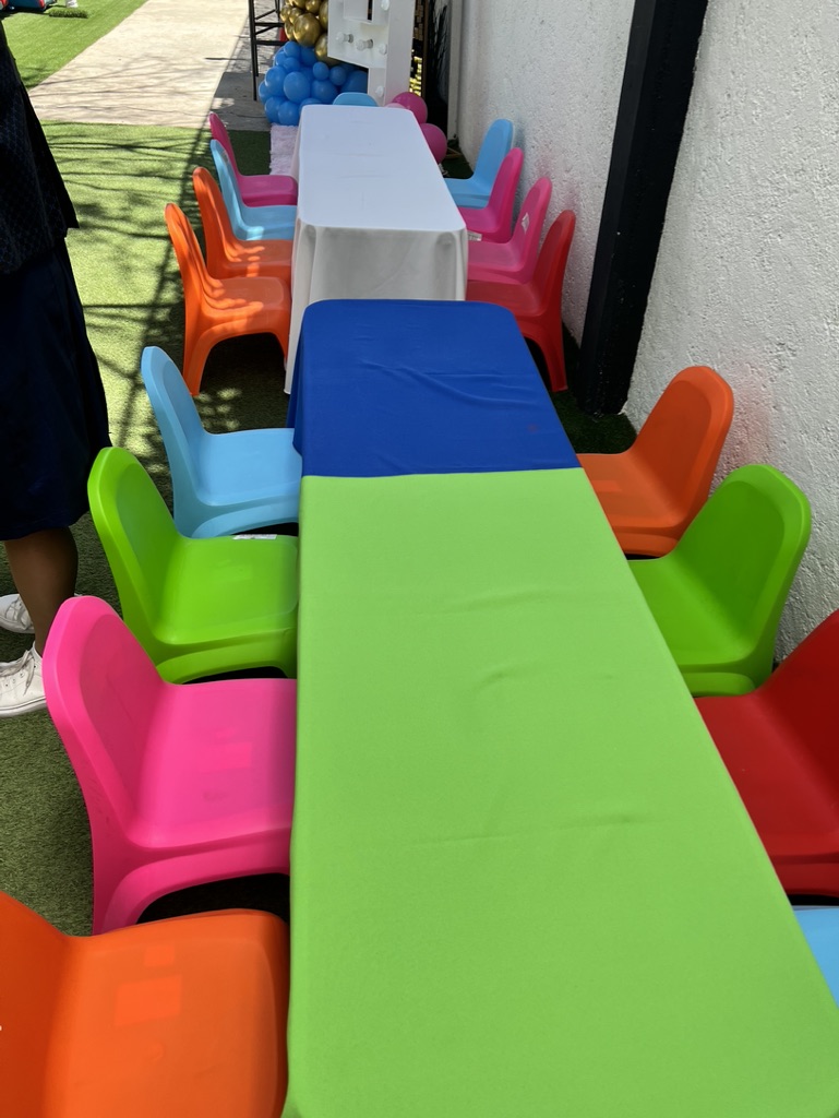 Mesitas y sillas infantiles de plástico en colores vivos junto al jardín
