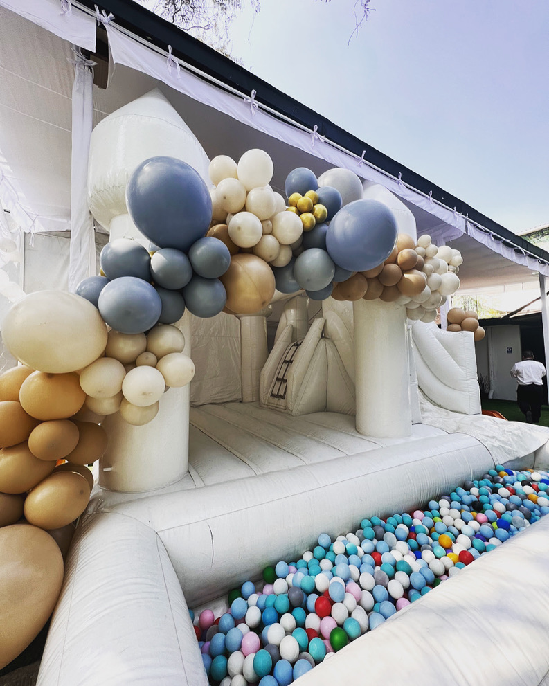 Juego inflable blanco con arco de globos y alberca de pelotas para niños