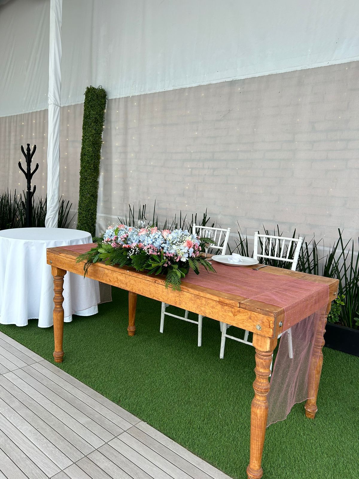 Mesa de honor de madera con arreglo floral y mantel de gasa rosa